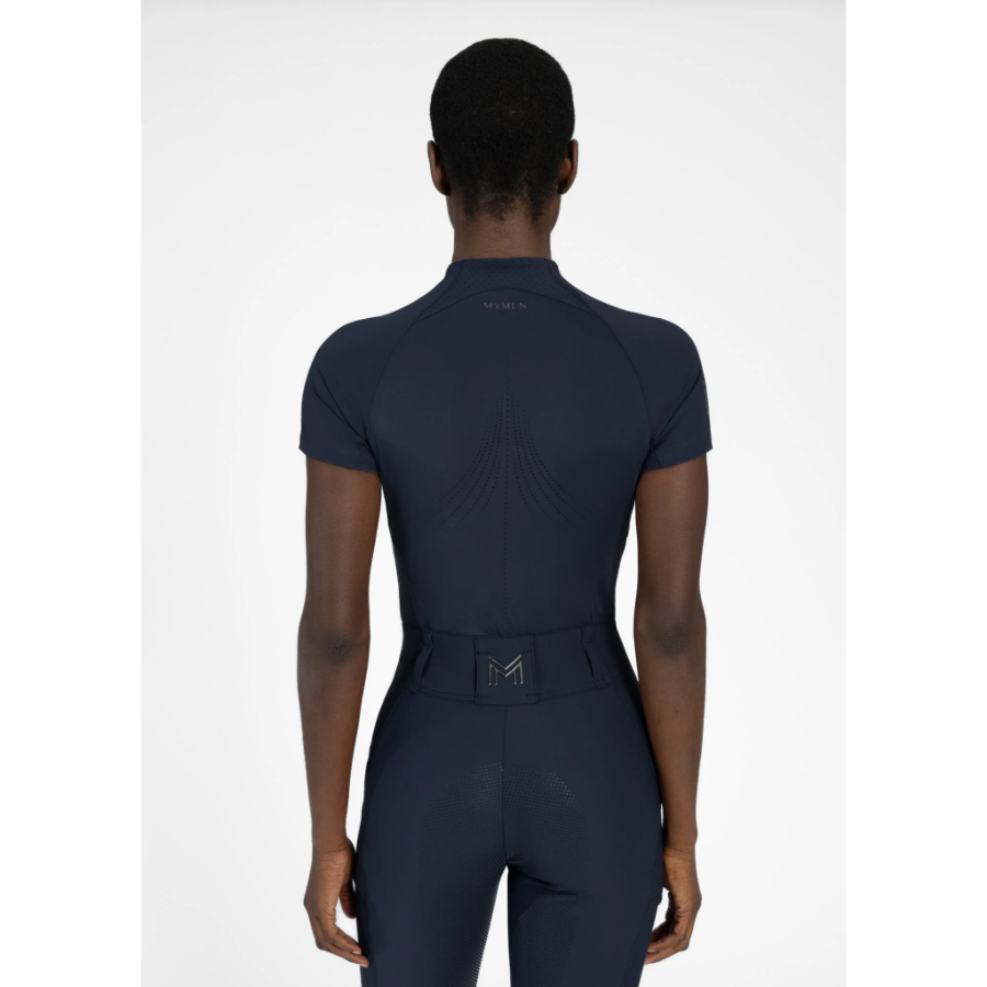 Model wearing black Maximilian Equestrian functional top on a white background, introducing the brand’s performance wear designed for movement in and out of the saddle.