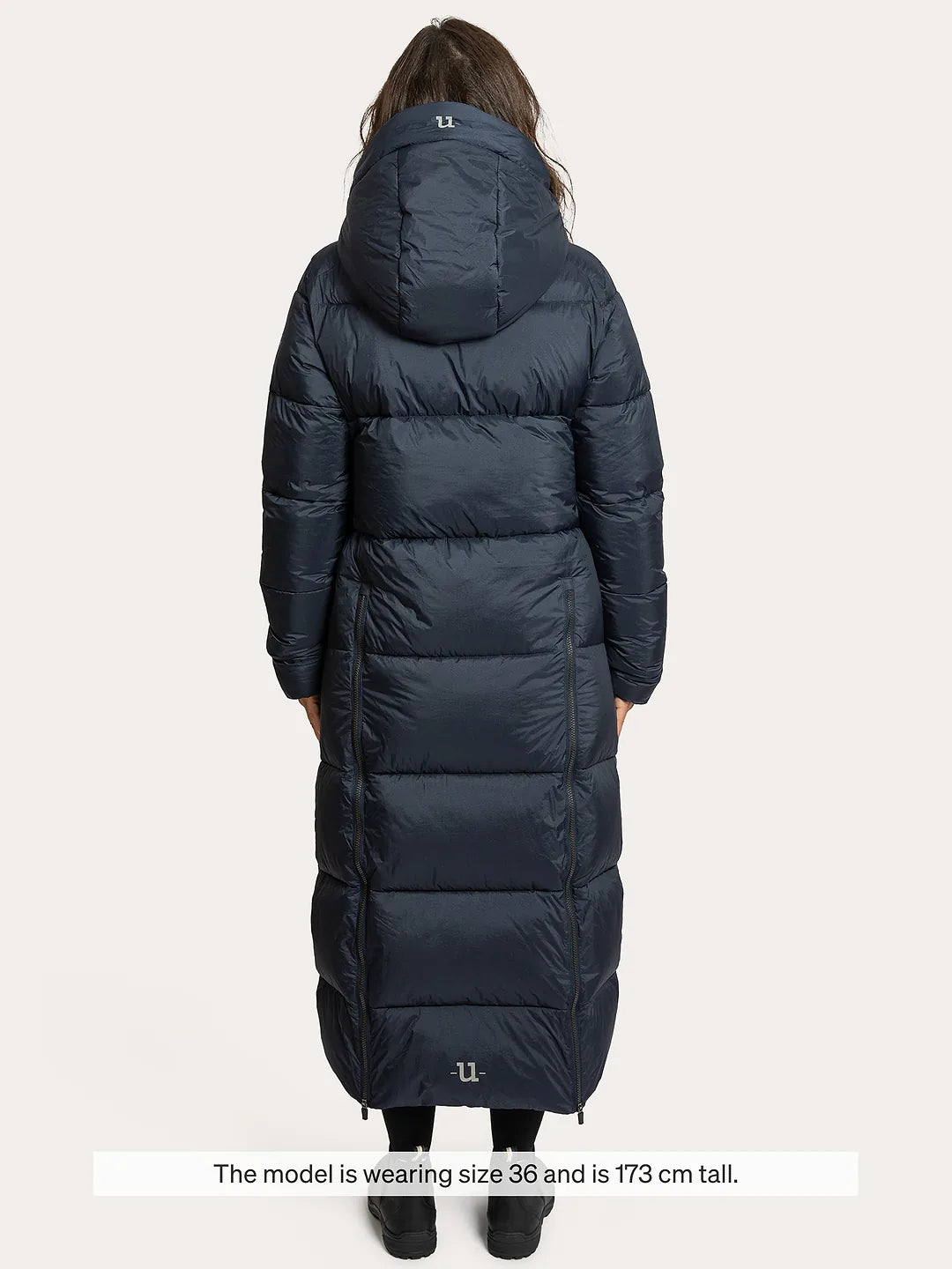 A model shown from the back wearing a Uhip arctic puffer coat extended eclipse. The image has a text overlay at the bottom stating 'The model wearing size 36 and is 173 cm tall.