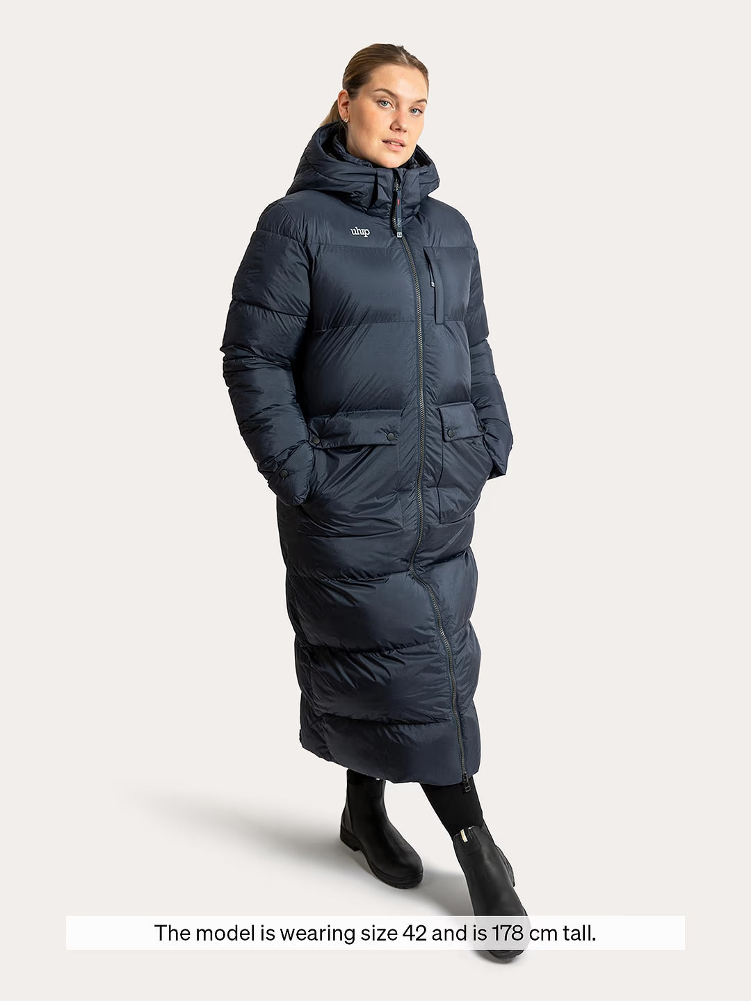 A woman modeling a Uhip arctic puffer coat extended eclipse with a hood, shown against a light gray studio background. A text banner at the bottom reads, 'The model is wearing size 42 and is 178 cm tall.