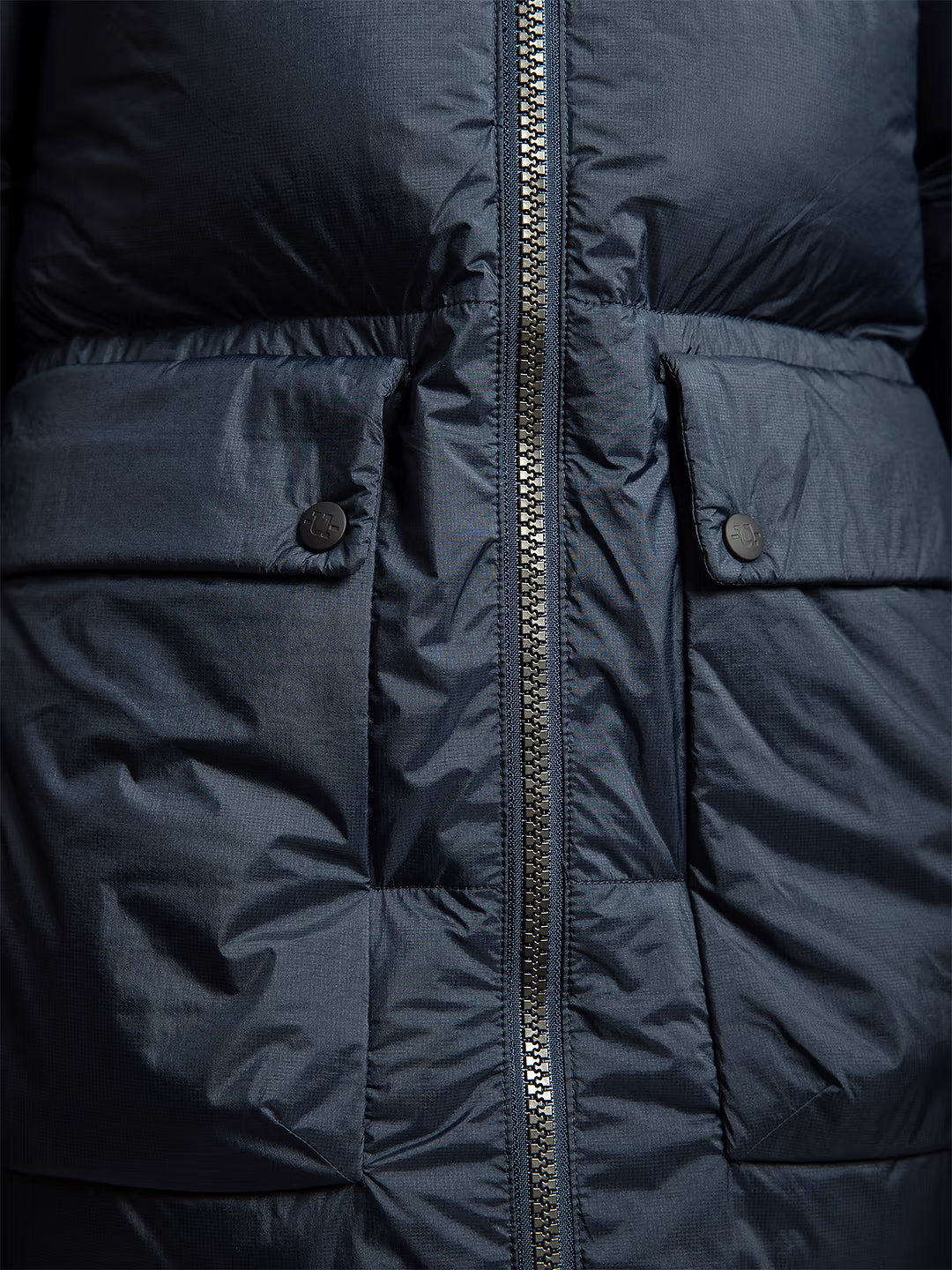 Close-up of Uhip arctic puffer coat extended eclipse showing the front zipper, quilted stitching, and flap pockets with metal snap buttons.