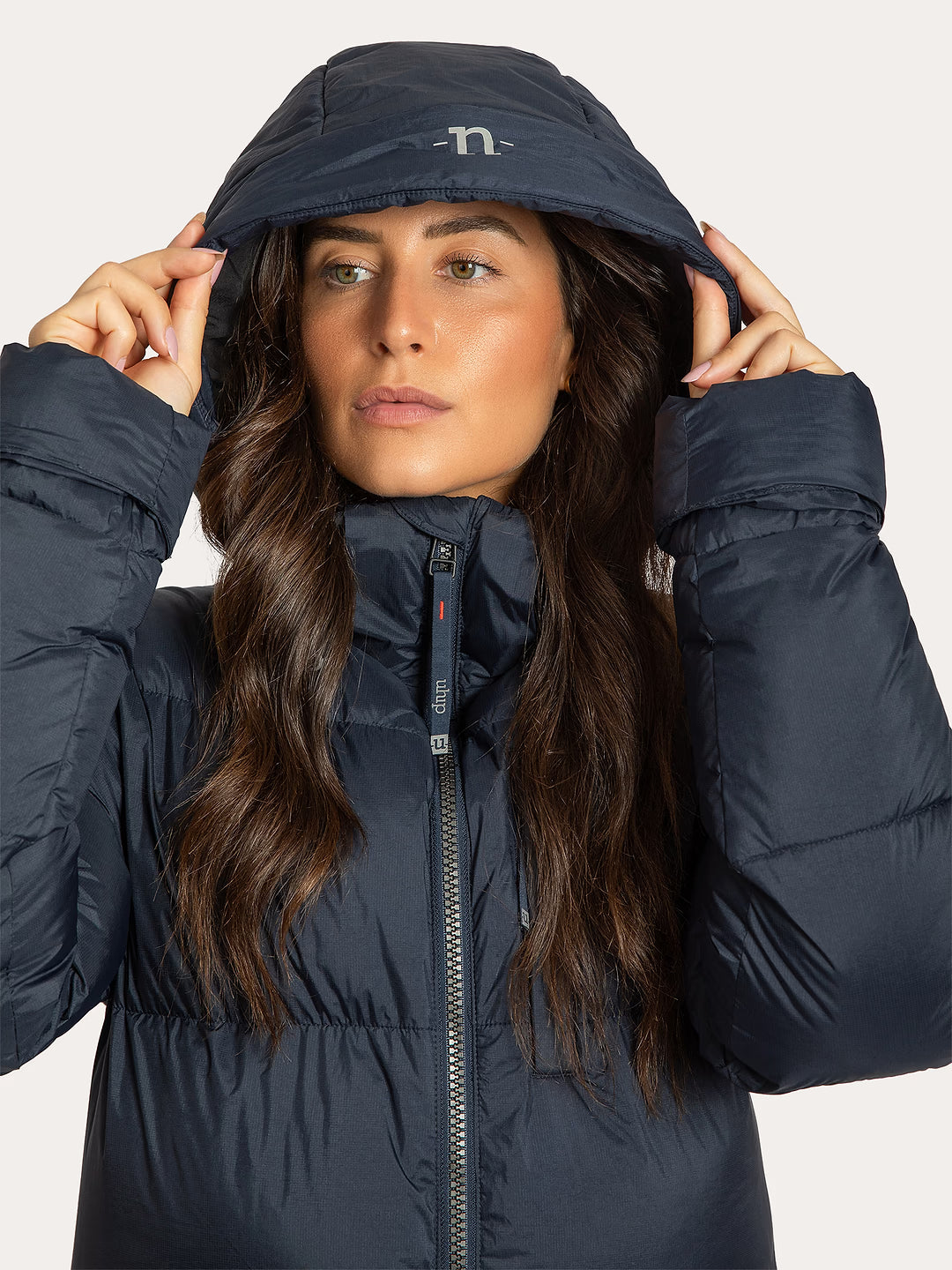 Woman wearing a Uhip puffer coat eclipse with a hood on a light grey background