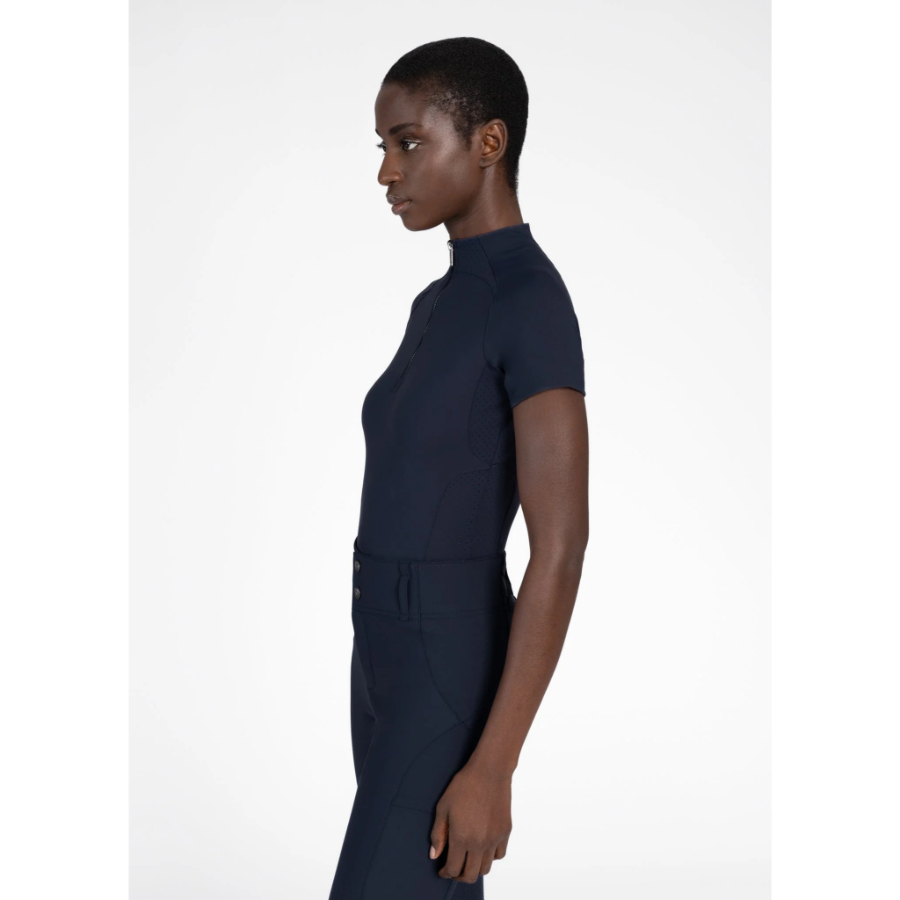 Model wearing black Maximilian Equestrian functional top on a white background, introducing the brand’s performance wear designed for movement in and out of the saddle.
