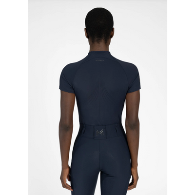 Model wearing black Maximilian Equestrian functional top on a white background, introducing the brand’s performance wear designed for movement in and out of the saddle.