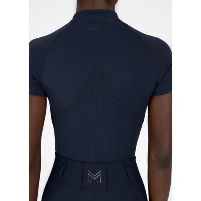 Model wearing black Maximilian Equestrian functional top on a white background, introducing the brand’s performance wear designed for movement in and out of the saddle.