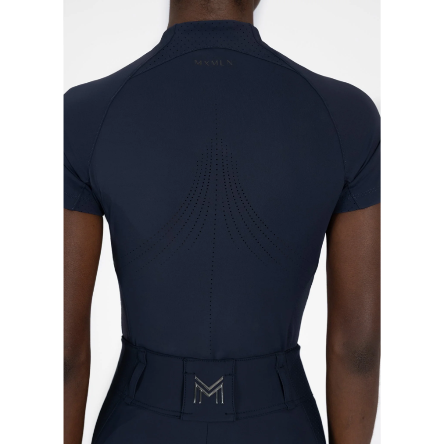 Model wearing black Maximilian Equestrian functional top on a white background, introducing the brand’s performance wear designed for movement in and out of the saddle.