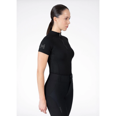 Model wearing black Maximilian Equestrian functional top on a white background, introducing the brand’s performance wear designed for movement in and out of the saddle.