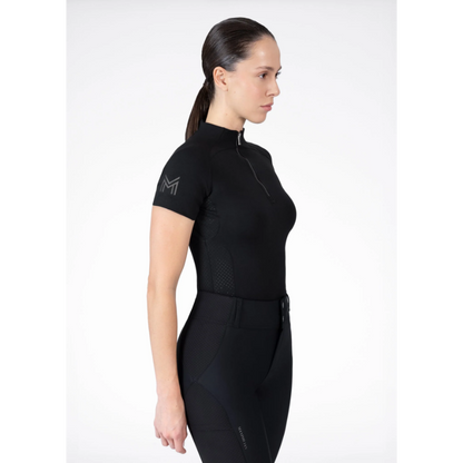 Model wearing black Maximilian Equestrian functional top on a white background, introducing the brand’s performance wear designed for movement in and out of the saddle.