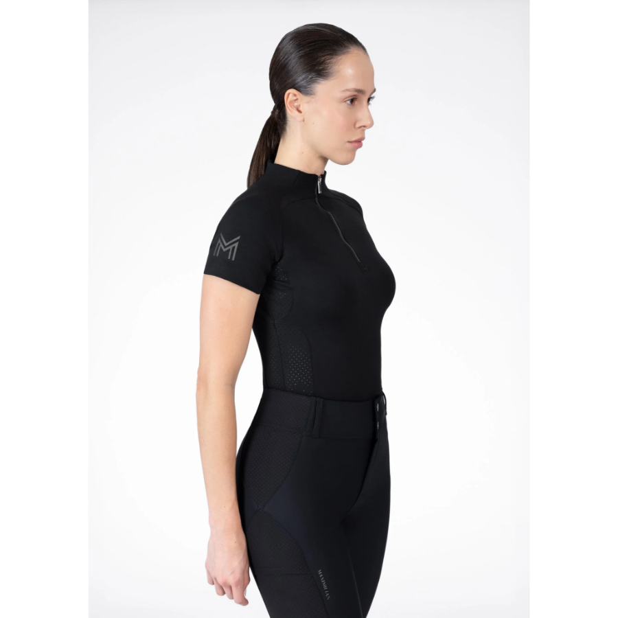 Model wearing black Maximilian Equestrian functional top on a white background, introducing the brand’s performance wear designed for movement in and out of the saddle.