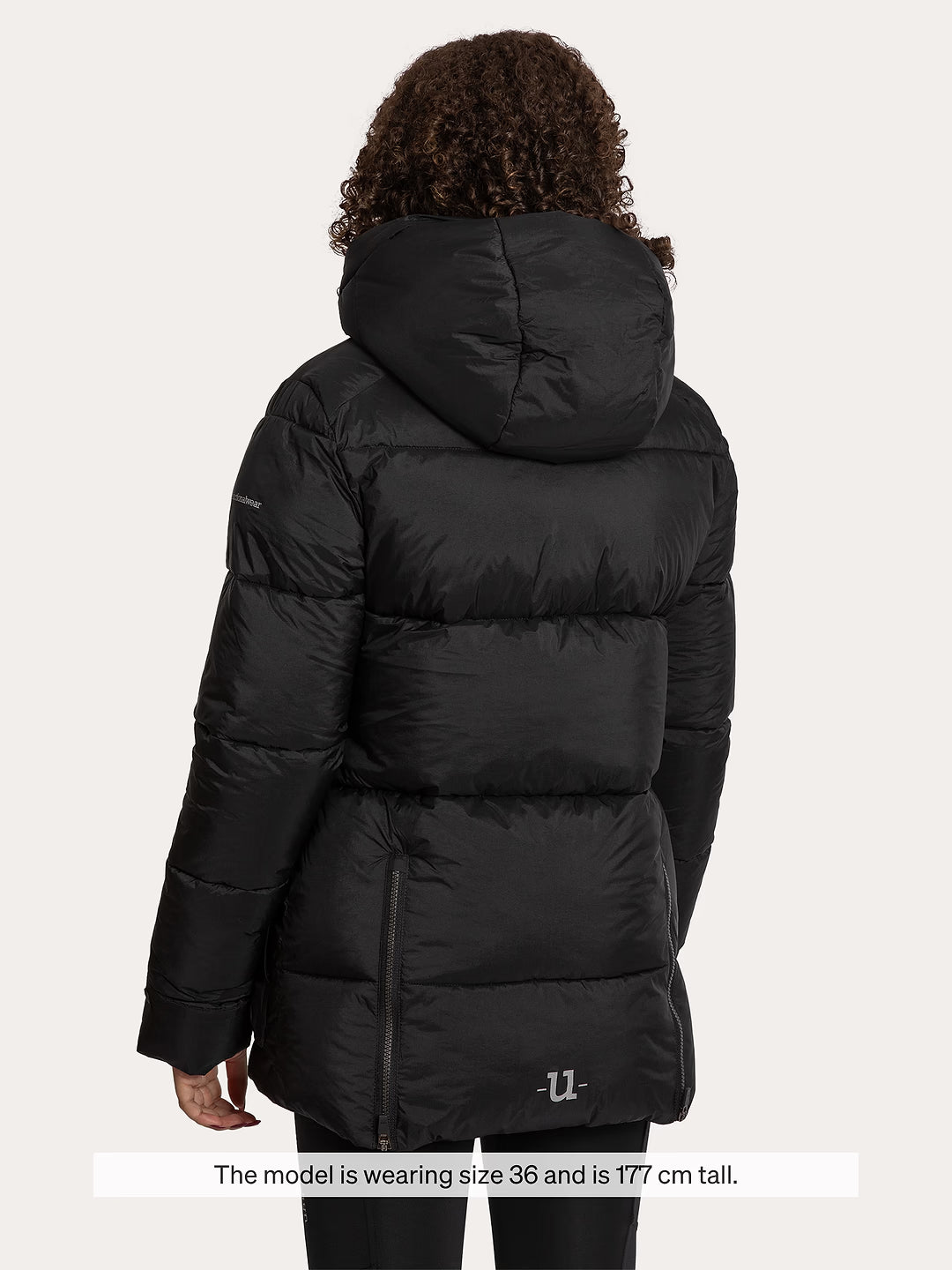 A model shown from the back wearing a Uhip Arctic Puffer Jacket Jet Black against a light grey background. A text overlay at the bottom reads 'The model wearing size 36 and is 177 cm tall.
