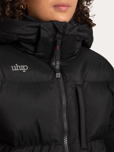 Close-up of a person wearing a Uhip Arctic Puffer Jacket Jet Black with a high collar, front zipper, and visible 'uhip'  reflective logo on the chest.