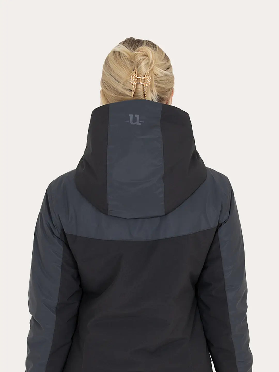 Rear view of a woman wearing a Uhip Reflective Jacket 2.0   against a light grey background.