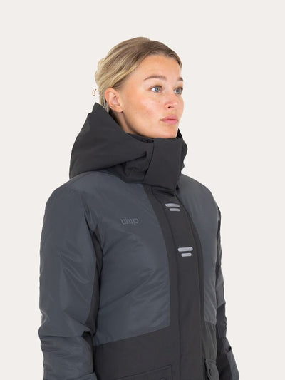 A woman wearing a Uhip Reflective Jacket 2.0  , shown in a side profile against a light off-white background.