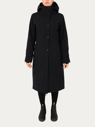 A model wearing a  Uhip Hailey Insulated Jet Black raincoat with front buttons, paired with black leggings and black ankle boots, against a light grey studio background.