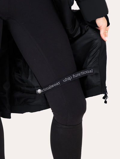 Close-up of a person wearing black athletic leggings and a Uhip Hailey Insulated Jet Black raincoat  showing a branded elastic band on the leg with the text 'Uhip functional wear'