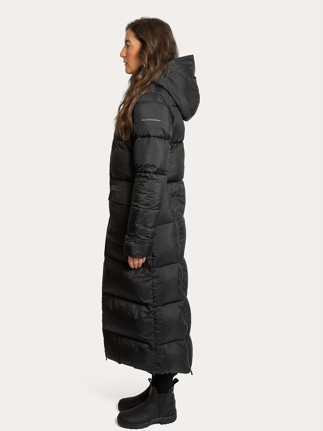 A woman shown in profile wearing a Uhip arctic puffer coat extended Black photographed against a plain light grey studio background.
