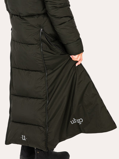 A close-up of a person wearing Uhip arctic puffer coat extended dark green with a side extending zippers, side pockets, and white embroidered 'uhip' logos near the lower hem, against a light off-white background.