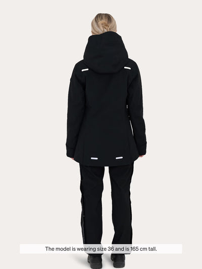 A model viewed from the back wearing a  black Uhip Rainy Jacket and matching black ski pants against a light grey studio background. A text overlay at the bottom reads, 'The model is wearing size 36 and is 165 cm tall.