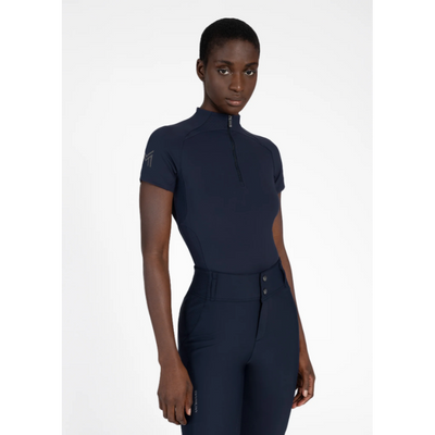 Model wearing black Maximilian Equestrian functional top on a white background, introducing the brand’s performance wear designed for movement in and out of the saddle.